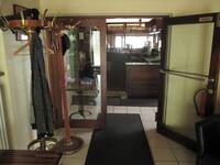 Eine offenstehende Glastür mit einer waagrechten Stange, links vor der Tür steht ein Kleiderständer