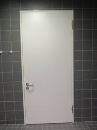 weiße Tür in einer gekachelten dunklen Wand