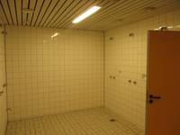 gekachelter Raum mit 4 Duschplätzen, rechts Tür zur Umkleide