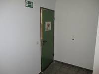 grüne Tür in einer weißen Wand, auf der Tür ein Aushang