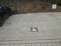 Gepflasterter Parkplatz mit Rollstuhlsymbol als Bodenmarkierung 