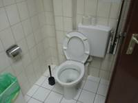 Eine weiße Toilette in einem weiß gekacheltem Raum